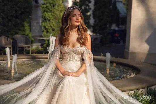 GENIVEVE Corset style beaded bodice with beaded tulle skirt. Shoulder drapes/ cape - Reflections Bridal Studio